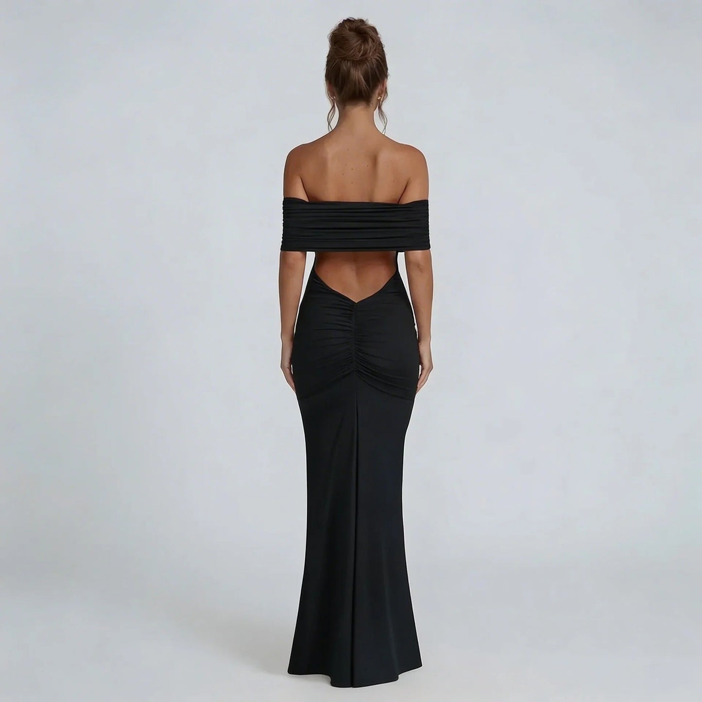 Black off-shoulder ruched maxi dress with ruched back seam — rear view showcasing bold open back and tapered silhouette.