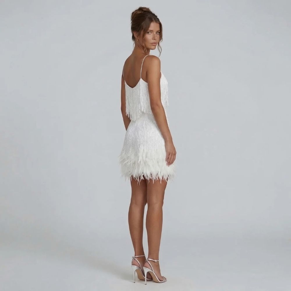 White fringe mini dress with feather-trim hem — back view highlighting V neckline and shimmering details.