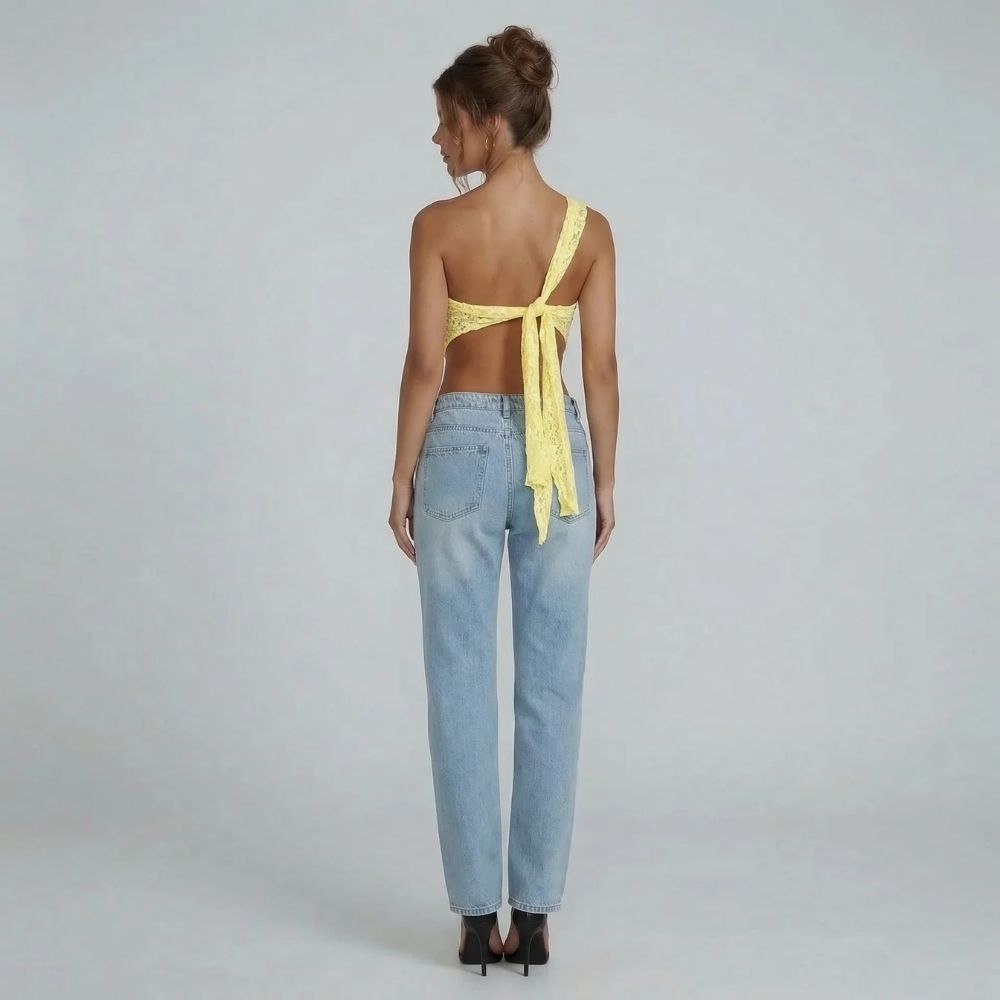 Cream floral lace asymmetric one-shoulder top with tie-back closure — back view showing adjustable fit and hem detail.