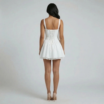 White corset-style mini dress with lace-up back detail and fitted bodice – back view.