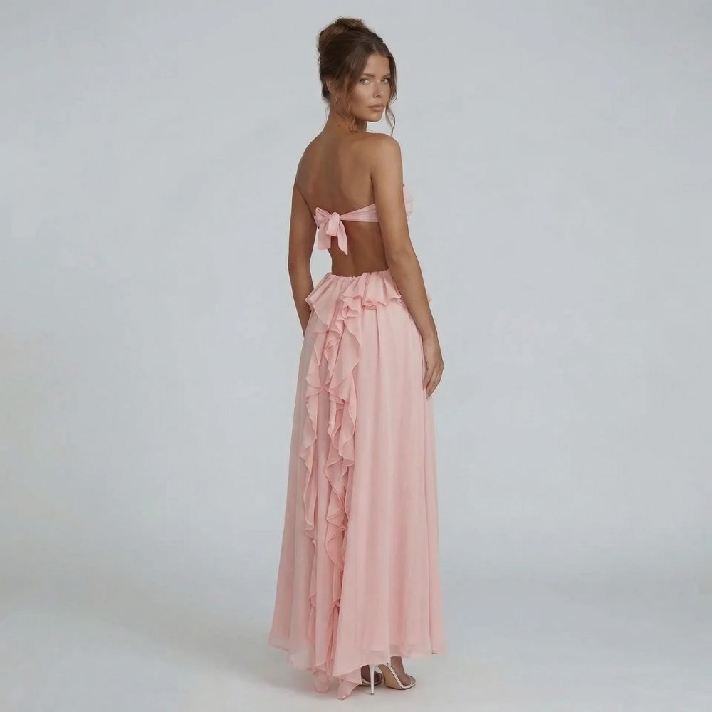 Back view of strapless blush pink maxi dress — bow-tied cutout waist and cascading chiffon ruffles.