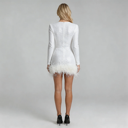 White sequin mini dress with feather-trim hemline — back view showing zip closure and sleek silhouette.