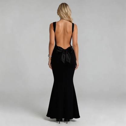 Black maxi dress featuring oversized back bow and dramatic open-back design — back view.