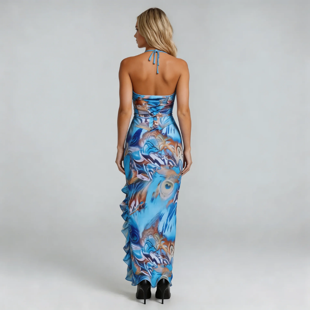 Blue feather-print maxi dress with thigh-high slit and cascading ruffle — styled with black heels.