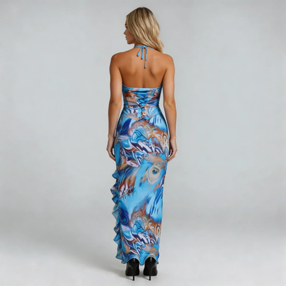 Blue feather-print maxi dress with thigh-high slit and cascading ruffle — styled with black heels.