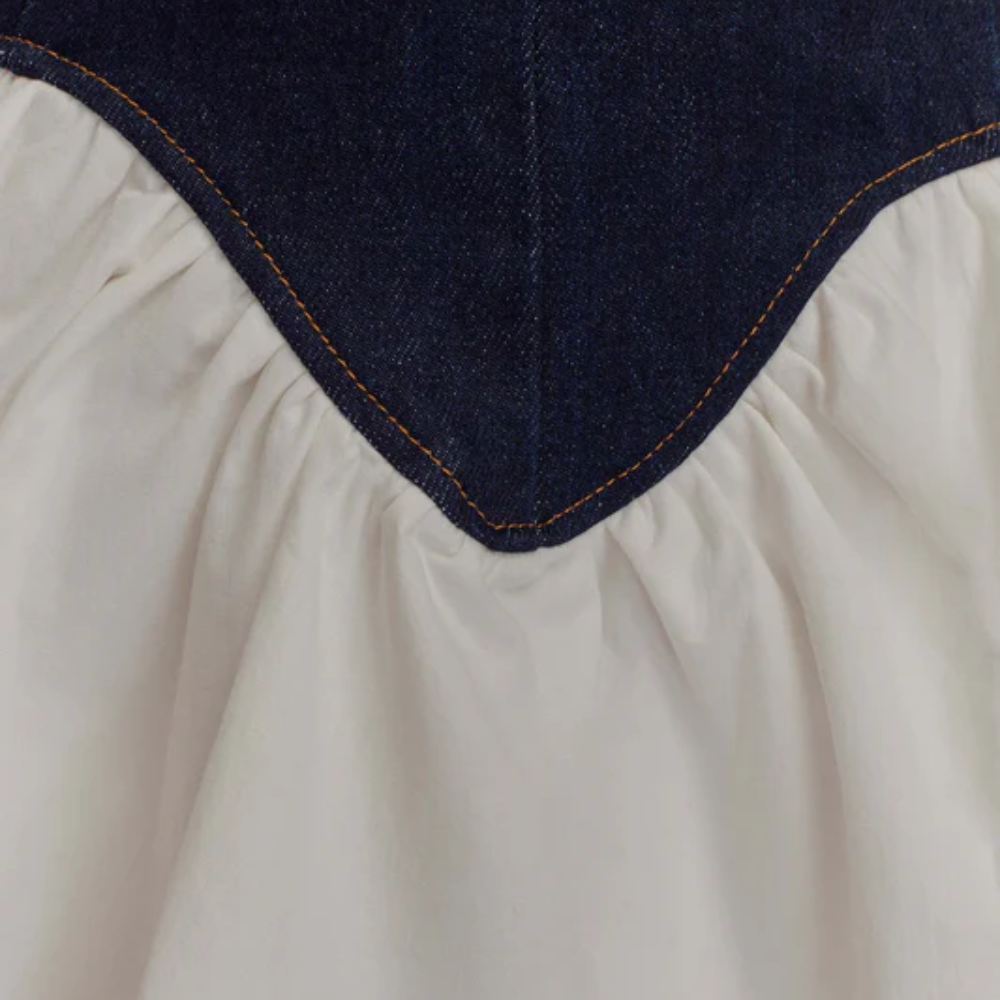 White and navy corset mini dress — close-up of structured denim-look bodice with gathered seam detail.