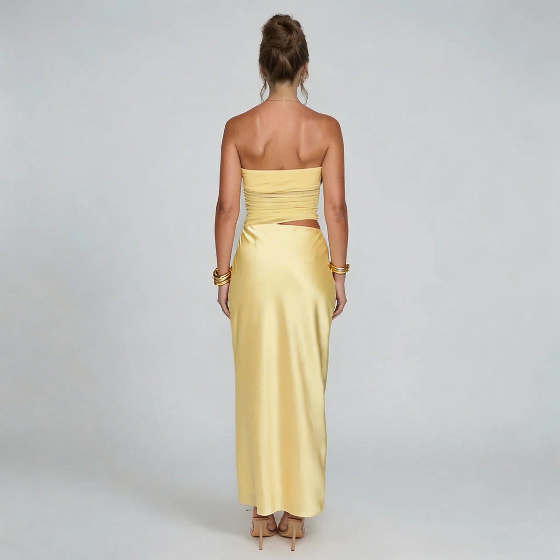 Yellow strapless ruched maxi dress — back view highlighting smooth skirt and asymmetrical cutout detail.