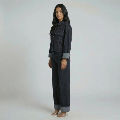 Side profile of the cropped jacket showing lapel-notched neckline and cuffed sleeves, paired with structured jeans.