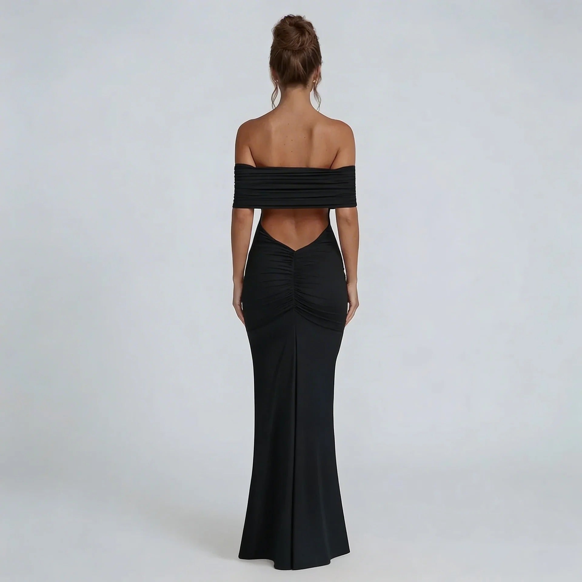 Black off-shoulder ruched maxi dress with ruched back seam — rear view showcasing bold open back and tapered silhouette.