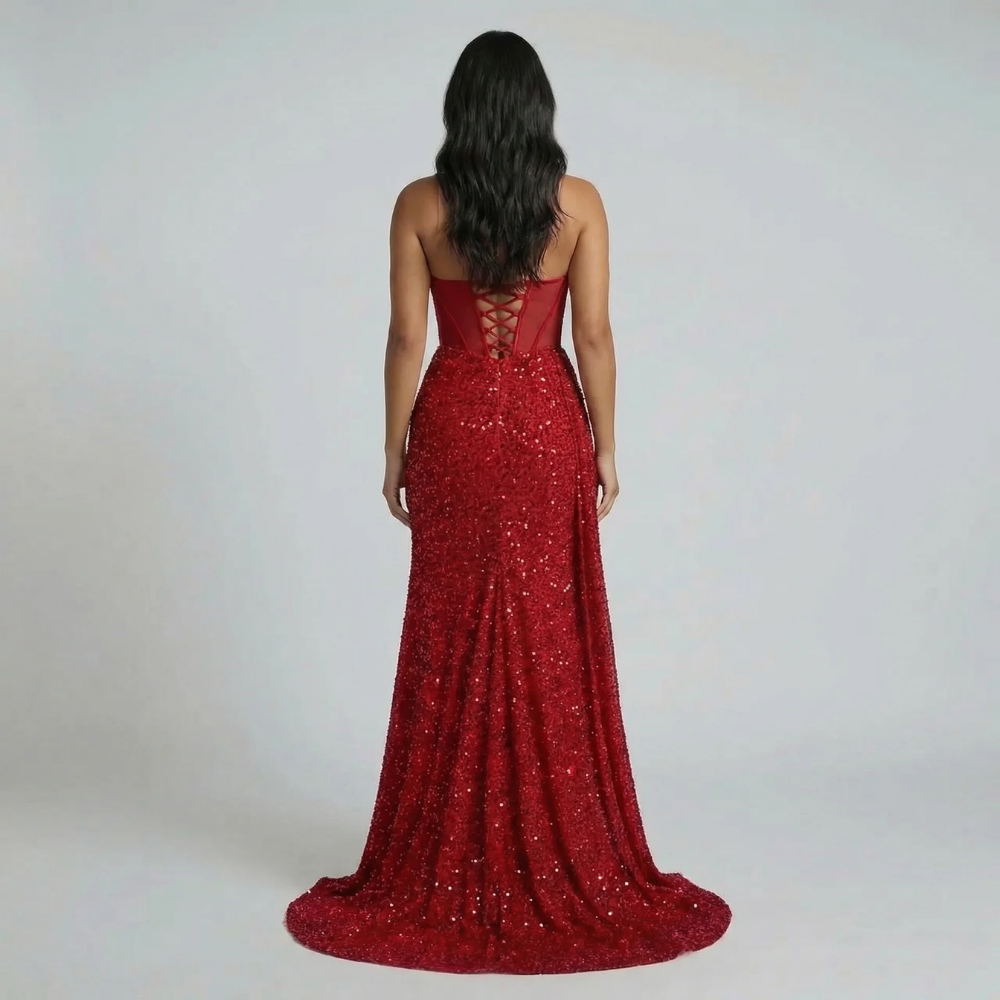 Back view of red sequin maxi dress—lace-up corset detail and elegant train visible.