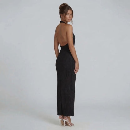 Black pleated maxi dress with open back — side angle highlighting backless silhouette.