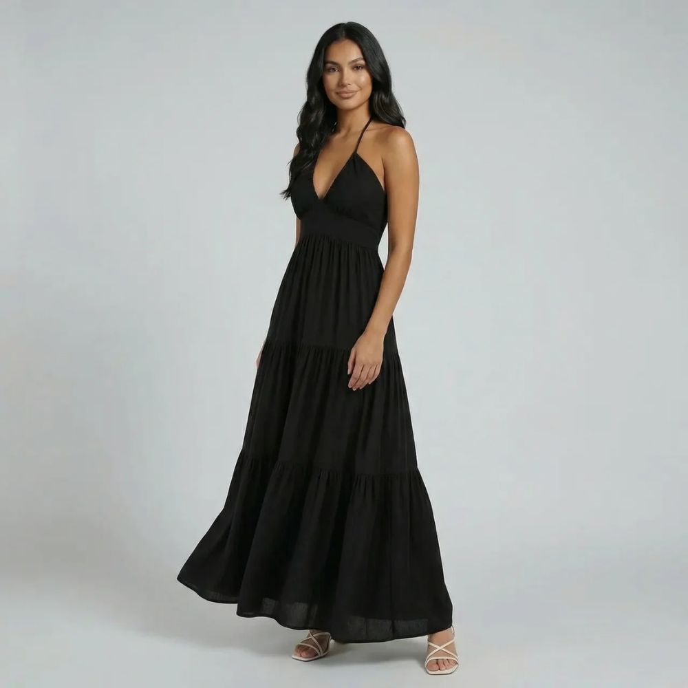 Black tiered maxi dress — angled side shot highlighting open back design and tiered movement of skirt.