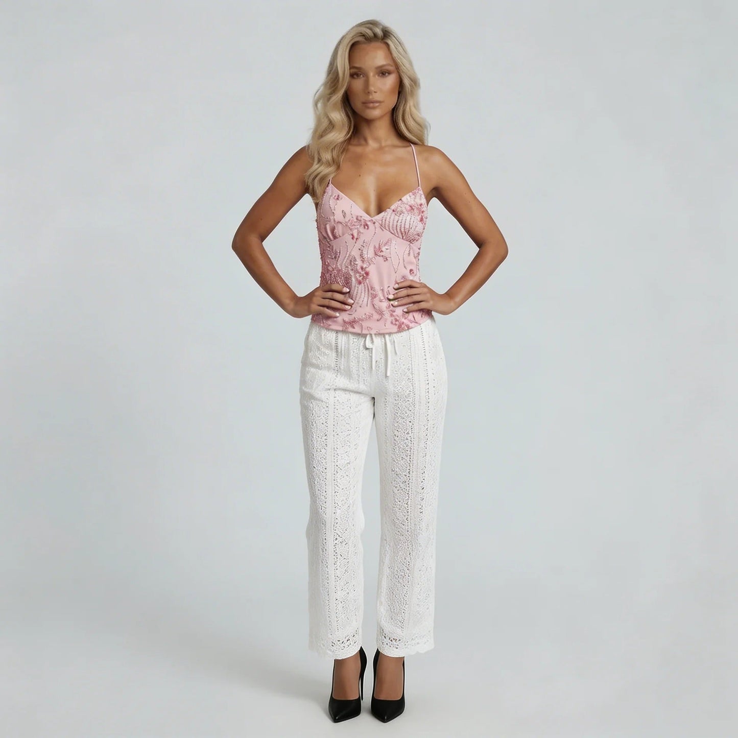 Women pink sequin cami top with spaghetti straps and beaded fringe detail, paired with white eyelet pants