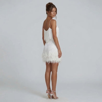 White fringe mini dress with feather-trim hem — back view highlighting V neckline and shimmering details.