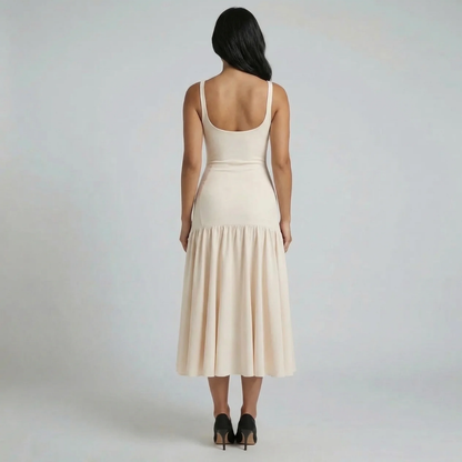 Beige flounce midi dress — back view highlighting drop-waist flounce hem and fitted cut.