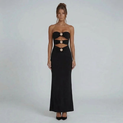 Black strapless maxi dress with bold cutouts and gold floral hardware accents — front view