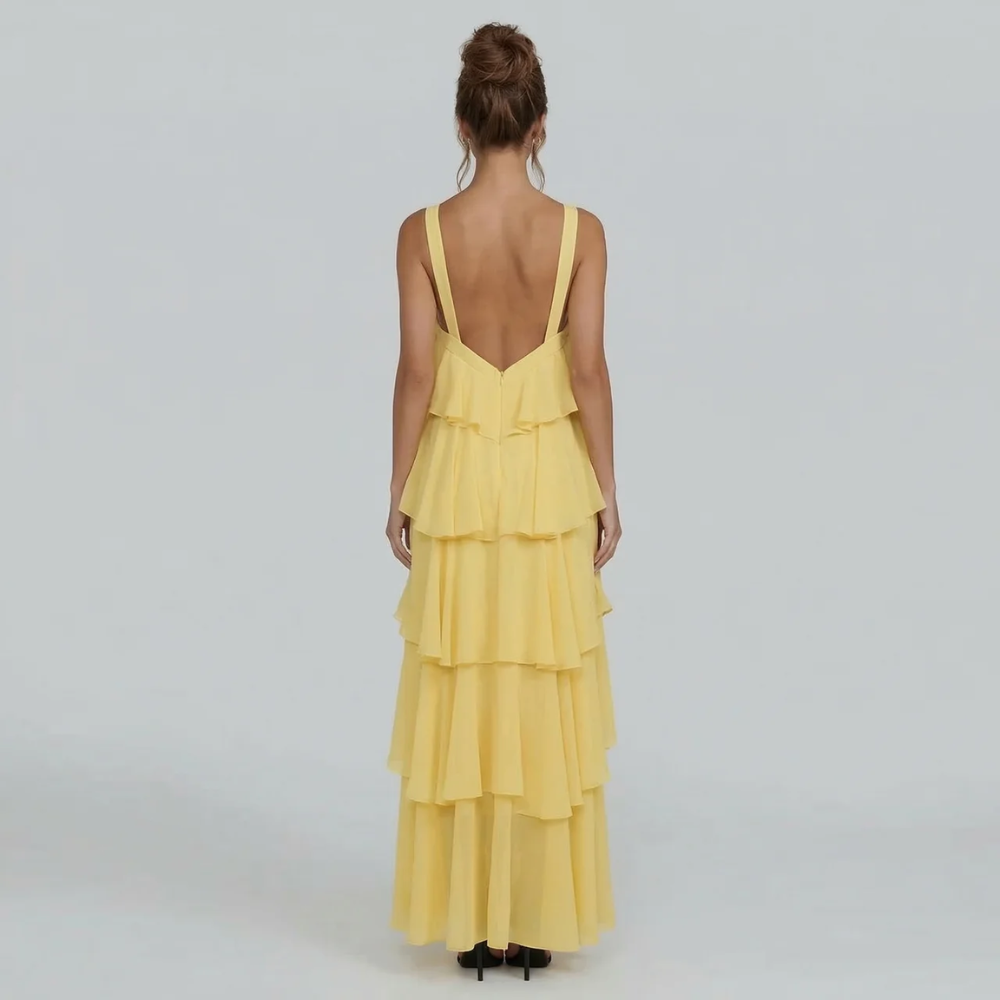 Back view of the yellow ruffled maxi dress, displaying the elegant open back and full tiered skirt.