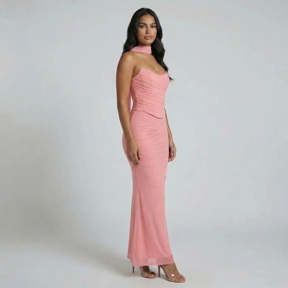 Pink ruched maxi dress with fluted hem and structured fit — angled side profile emphasizing details.