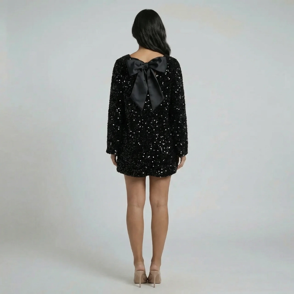 Black sequin shift mini dress with oversized black bow detail — back view showing elegant bow feature.
